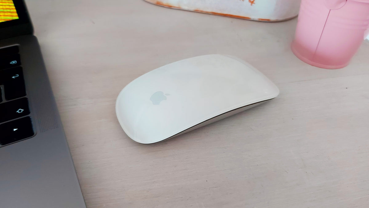 Apple Magic Mouse 1 detalle lateral junto a MacBook